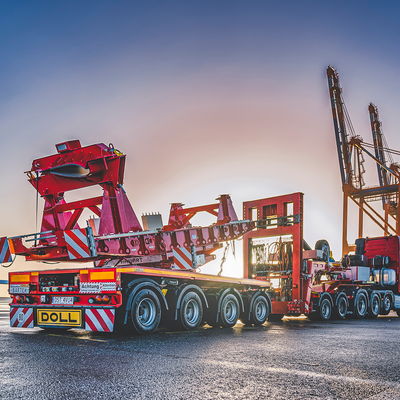 Schwertransportfahrzeug von DOLL für Windkraftanlagen am Hafen bei Sonnenuntergang