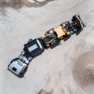 Aerial view of a truck loaded with a construction site vehicle negotiating a bend