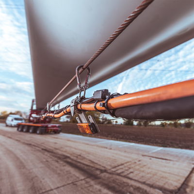 Nahaufnahme der Sicherung eines Windturbinenblatts mit Kabeln und Karabinern an einem DOLL-Schwertransport.