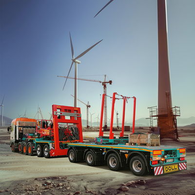 DOLL Nachläufer-Kombination mit Anhänger für Windkraftanlagen beim Aufbau eines Windparks mit Kränen im Hintergrund.