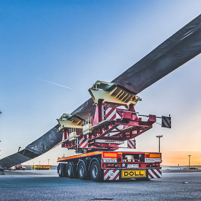Schwertransportfahrzeug von DOLL für Windkraftanlagen am Hafen bei Sonnenuntergang