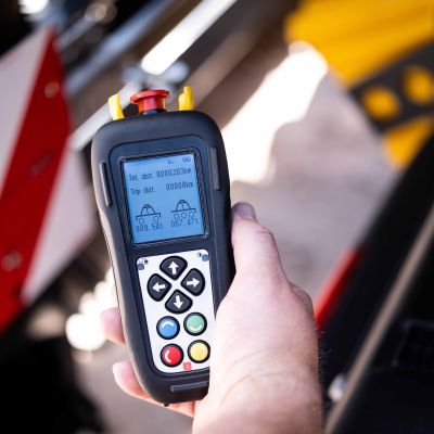 One hand holds the DOLL connect radio remote control with vehicle data shown on the display