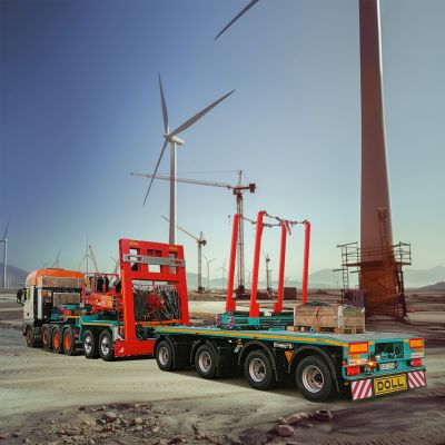 DOLL trailer combination with trailer for wind turbines during the construction of a wind farm with cranes in the background.