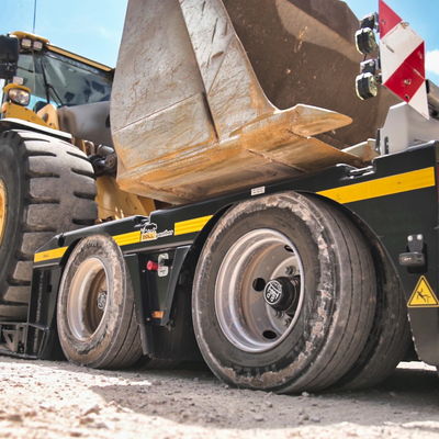 Arrière de la semi-remorque surbaissée DOLL, chargée d'un véhicule de chantier avec la hauteur de chargement la plus basse